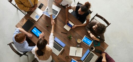 Top view of a diverse team collaborating in an office setting with laptops and tablets, promoting cooperation.