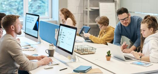 Team collaboration in a modern office setting with computers and diverse employees working together.